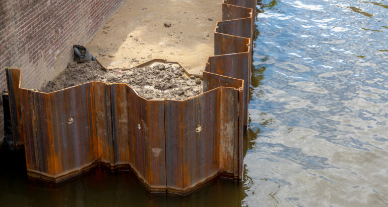 Amsterdam canal wall maintenance, Rusted steel sheet surrounded the wall to separate water for repair, Construction side work along the water, Netherlands